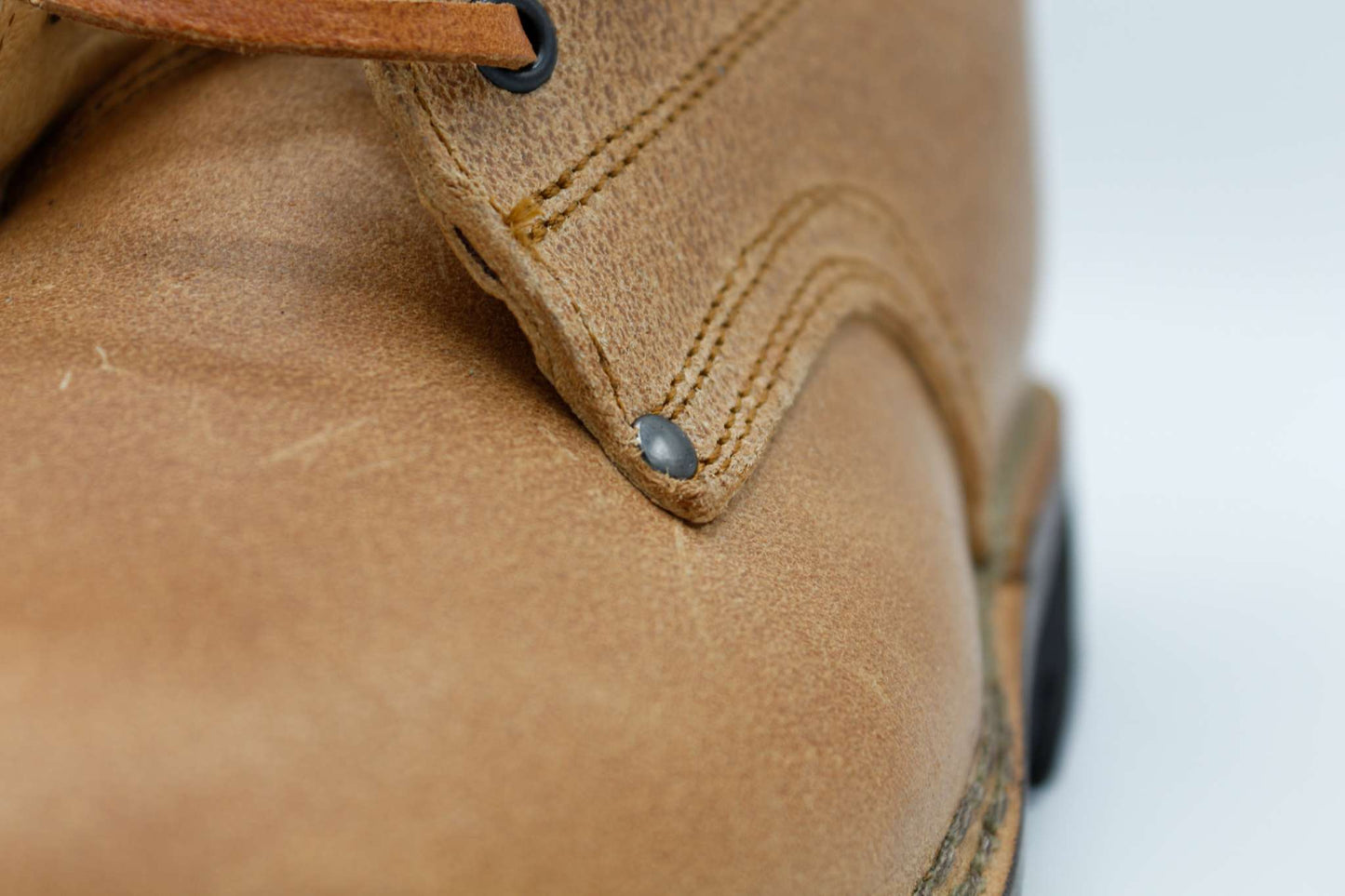 close-up of handcrafted natural leather work boot with double stitching and black rivet, breathable vacchetta leather scarpon in cuoio